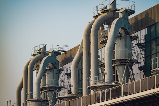 Aerial view of an industrial carbon capture facility with pipes and storage tanks, surrounded by empty fields.