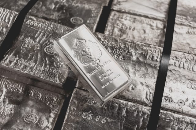 Stack of silver bullion bars reflecting light on a dark surface
