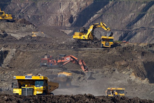 BHP's 130-Year Evolution from Australian Mine to Global Giant Aerial view of a large open-pit iron ore mine in Western Australia with heavy machinery and haul trucks operating on terraced levels.