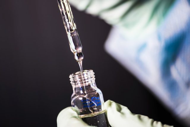 A scientist examines a molecular model of the IDH1 enzyme in a laboratory, with a small molecule inhibitor binding to the mutated site.