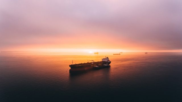 Singapore skyline at sunrise with cargo ships in the harbor, representing the city-state's trade-driven economic recovery in 2021.