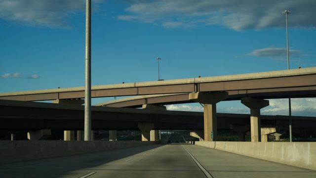 A collapsed section of Interstate 95 in Philadelphia with twisted concrete and steel, emergency vehicles nearby, and traffic diverted to alternative routes.