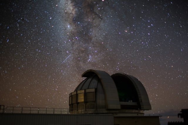 A graduate student points at a telescope image showing a newborn exoplanet in its early formation stage.