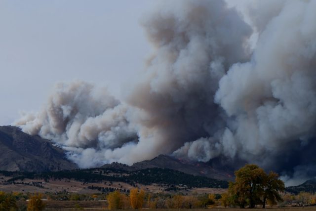 Search and rescue teams walk through charred forest debris and burned homes after a deadly wildfire