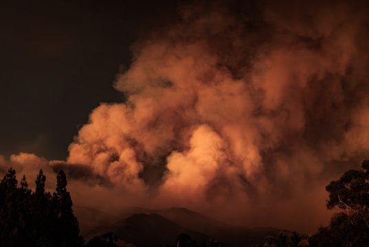 Hughes Fire Burns 5,000 LA County Acres, Evacuations Ordered Orange flames race up dry hills toward Castaic Lake as smoke towers over fleeing traffic and emergency vehicles.