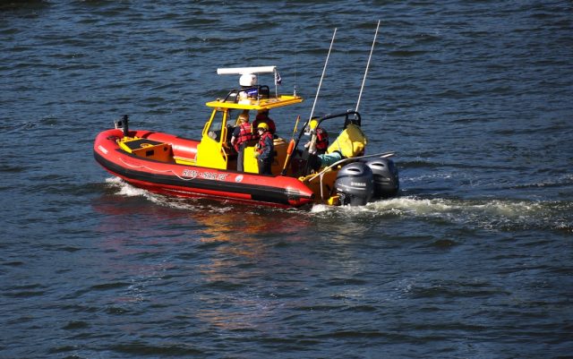 A rubber boat capsizes in rough seas off the coast of Bodrum, with rescue workers approaching in a small vessel.