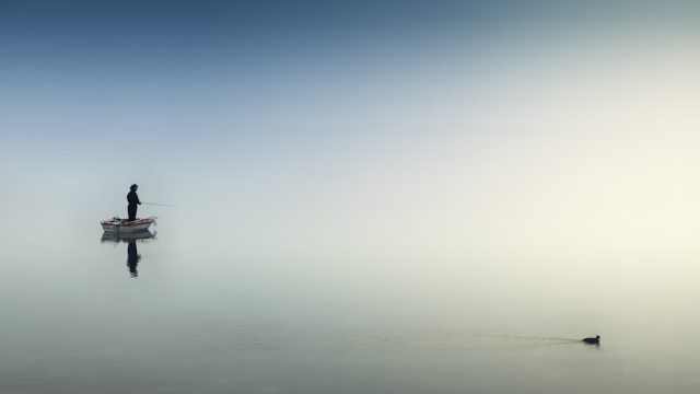 A fishing boat navigates rough seas off the coast of Gloucester, Massachusetts, under a gray sky.