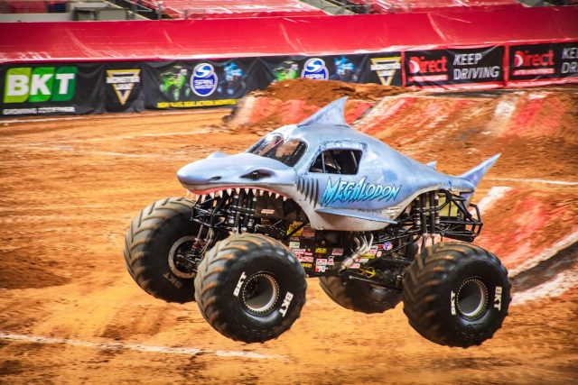 Investigation Focuses on Safety Measures After Colombia Monster Truck Crash A large monster truck with oversized tires sits on a dirt track, surrounded by crowd barriers and spectators.