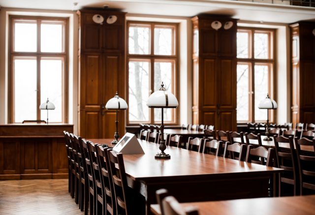 A Malaysian judge in a courtroom reviewing legal documents related to a corporate restructuring case.
