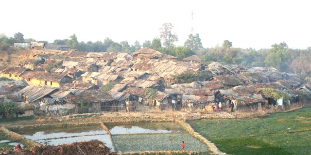 Firefighters battle a blaze at the sprawling Kutupalong refugee camp in Bangladesh, with smoke rising over rows of shelters.