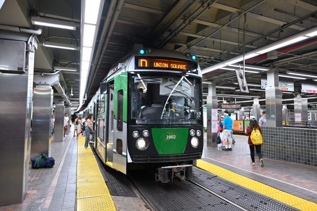 A derailed Green Line train in Somerville with emergency responders and injured passengers being assisted near the tracks.