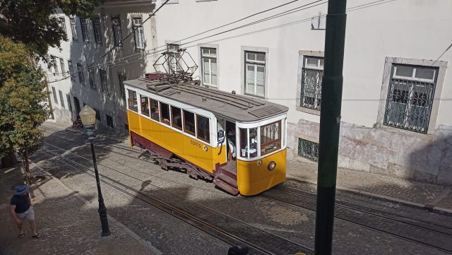 Rescue crews work beside the Ascensor da Glória funicular after it slammed into a downtown Lisbon building, with debris scattered across the steep street.