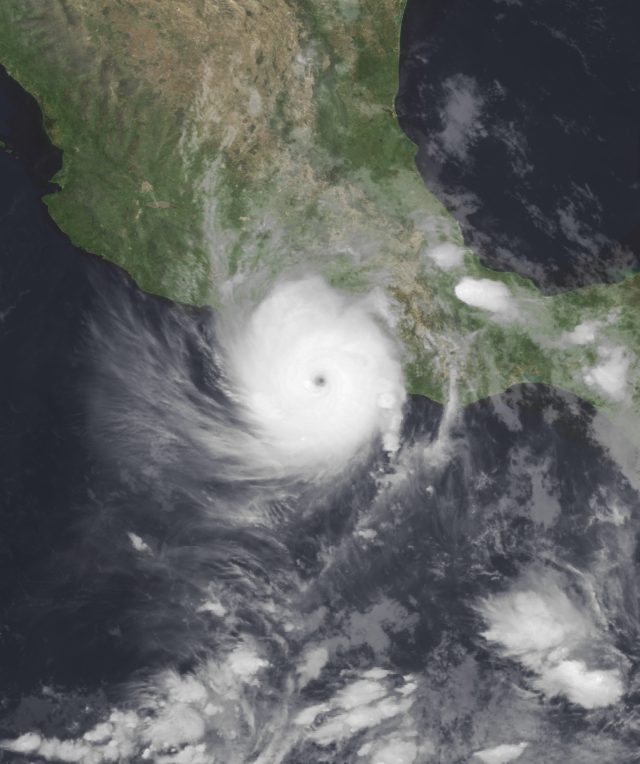 Collapsed high-rise hotels and debris-strewn Acapulco beachfront under dark post-hurricane skies.