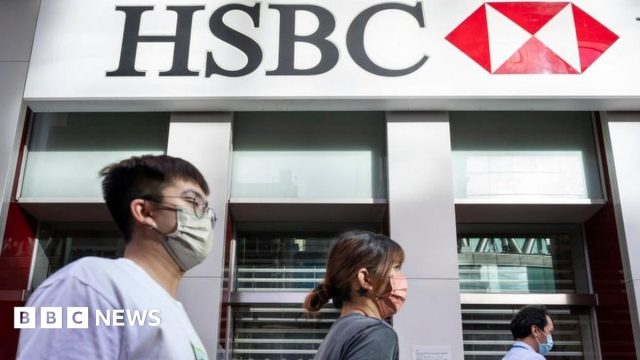 HSBC headquarters entrance with London City workers passing penalty headlines on phone screens.