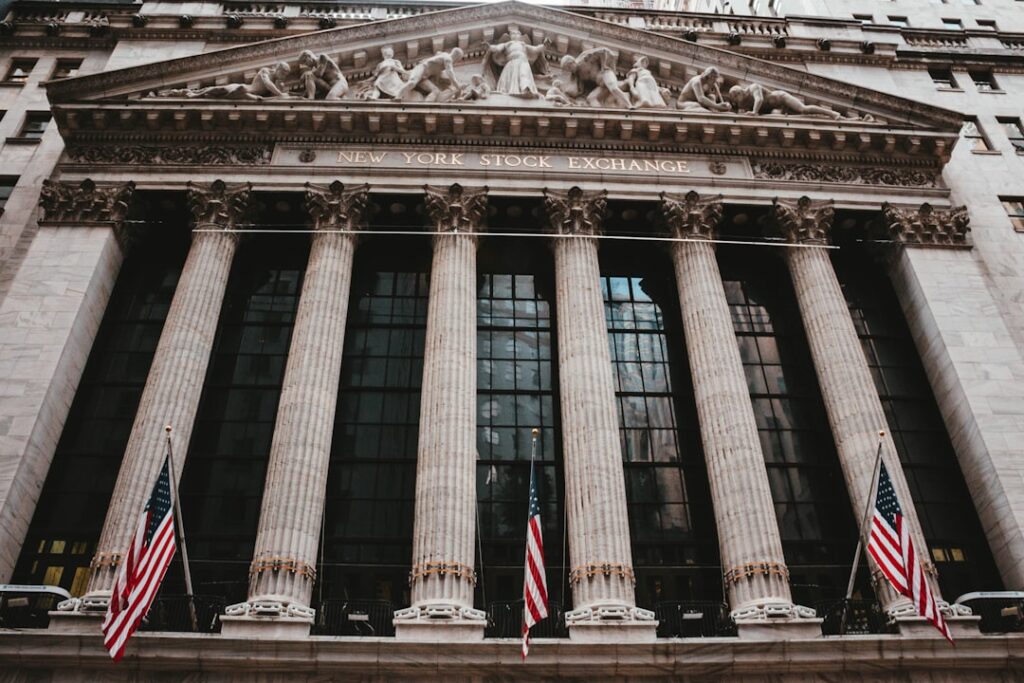 Traders on a stock exchange floor watch screens displaying red numbers during a market sell-off.