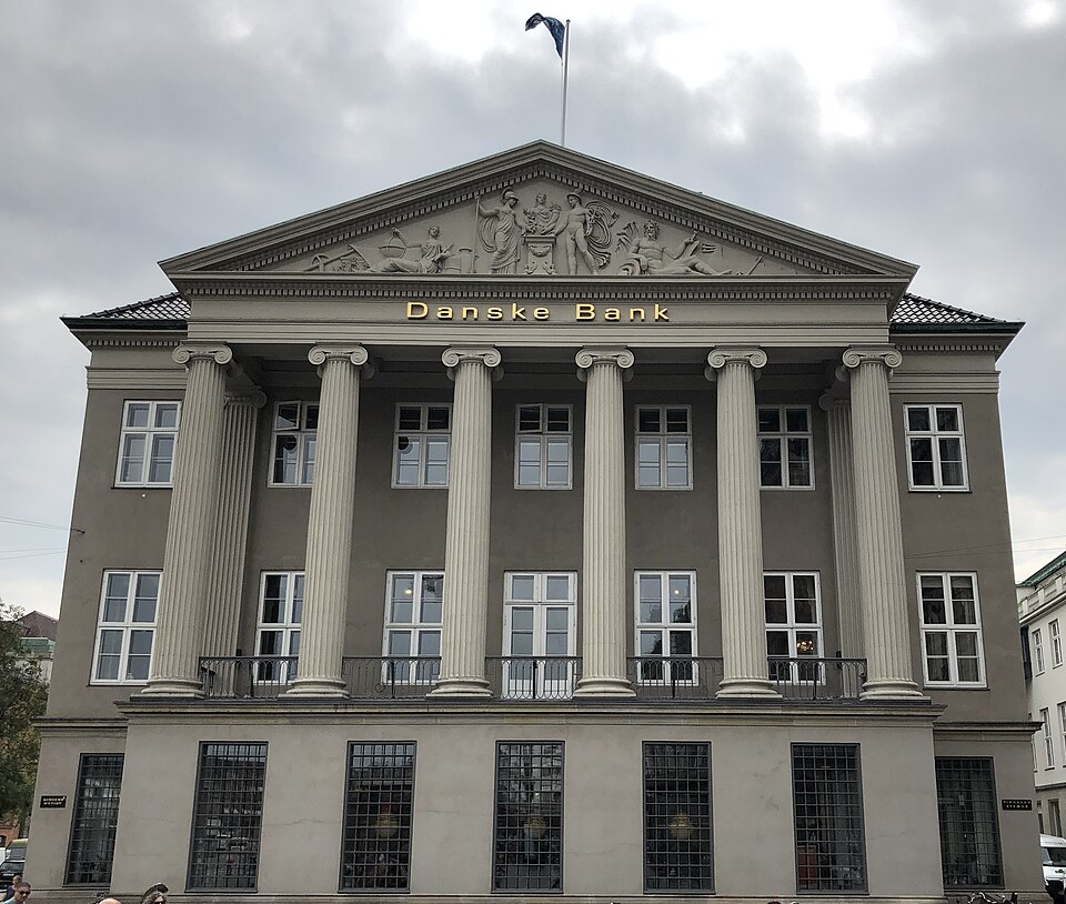 Danske Bank headquarters in Copenhagen under grey sky, press crews outside after guilty plea announcement.