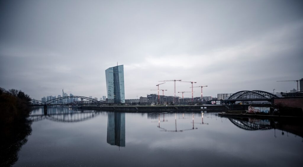 European Central Bank building in Frankfurt with euro symbol on facade under cloudy sky.