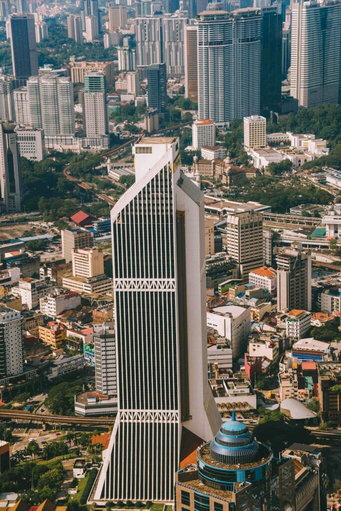A modern bank building in Kuala Lumpur with the Petronas Towers visible in the background under a clear sky.