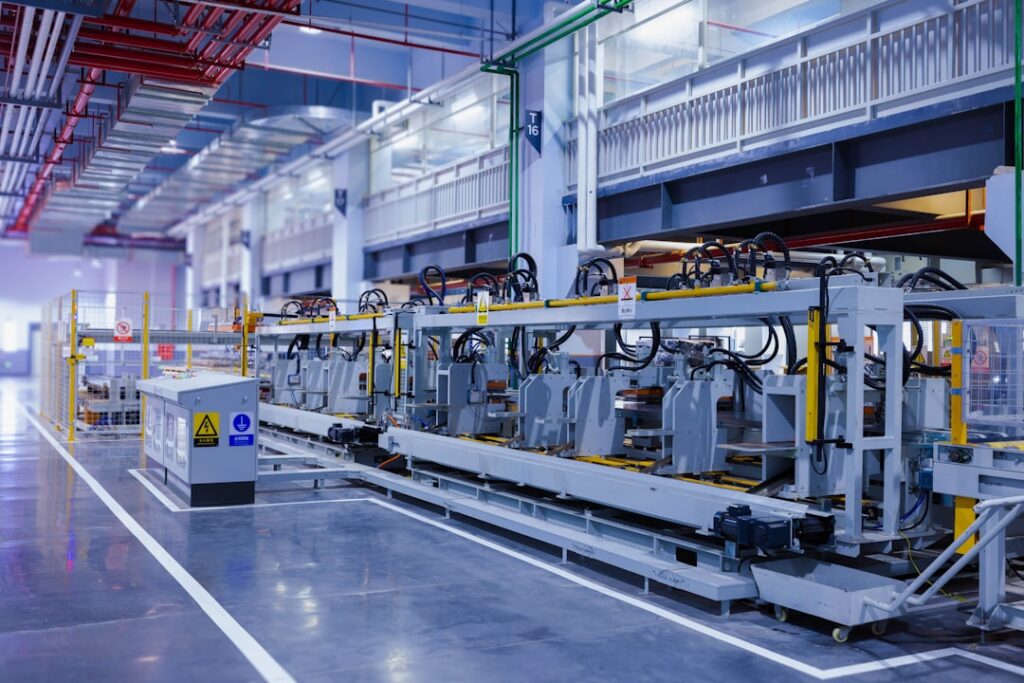 Idle Renault assembly line in Wuhan factory with unfinished cars and motionless robotic arms under dim lights.
